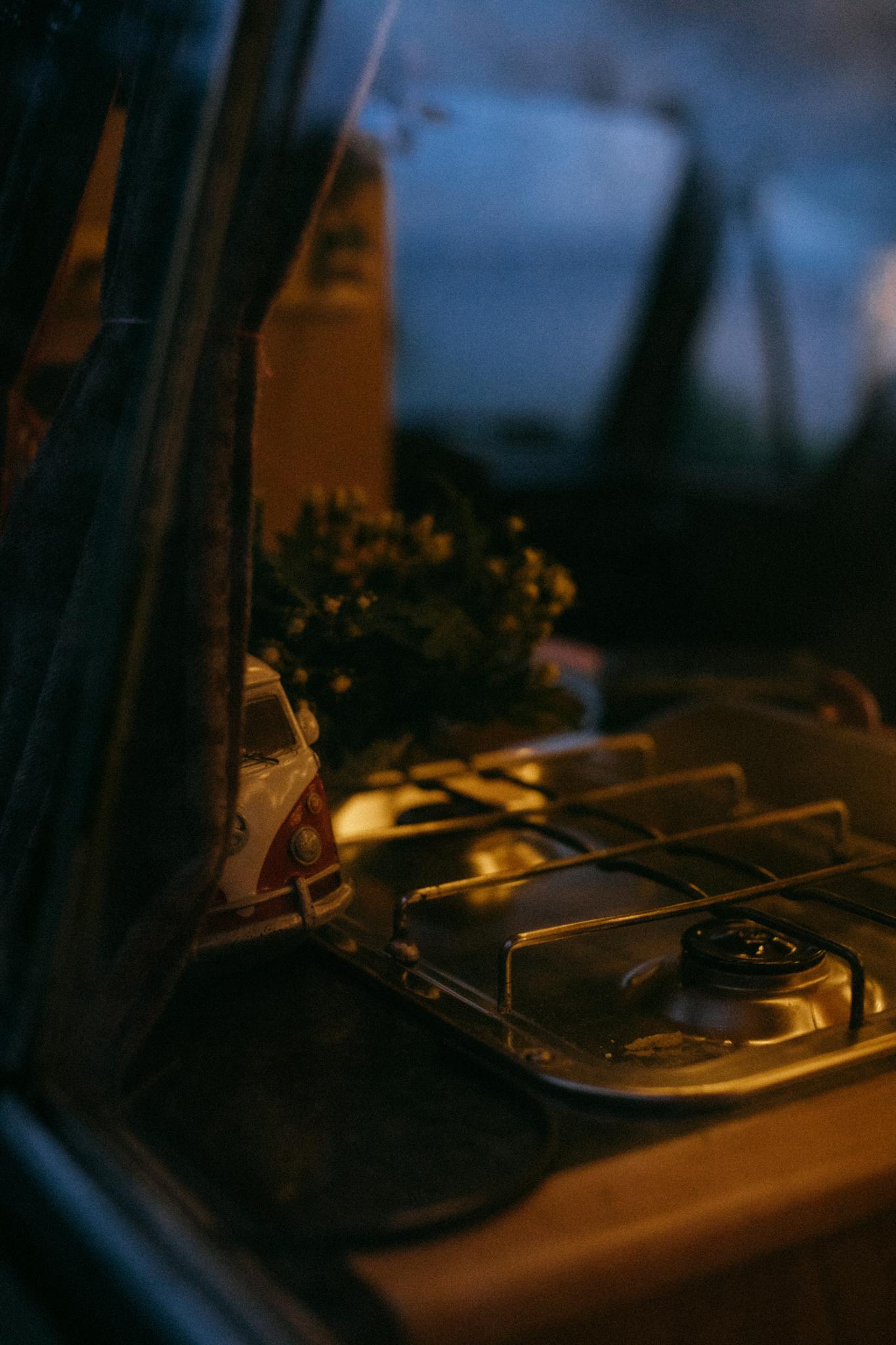 A warm evening view of a van's cozy kitchen setup with a stove and plants, capturing the essence of van life.